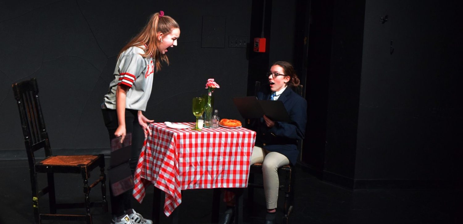 two students on stage during student directed play