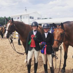 Two riders holding ribbons in front of their horses