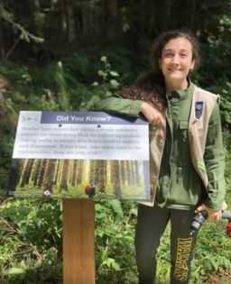 Ally Pelayo '20 posing with a plaque explaining her project