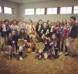 Riders posing in the barn with their ribbons
